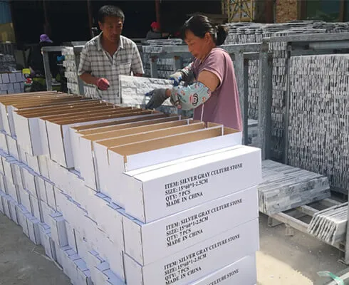 Workers packing stacked stone panels into boxes for delivery